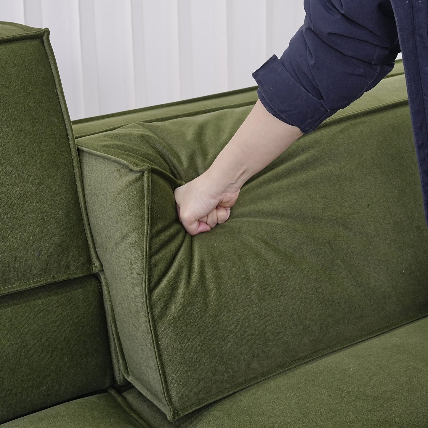 Hand pressing down on the adjustable backrest portion for Cubix fabric adjustable backrest sofa in green pet friendly fabric.