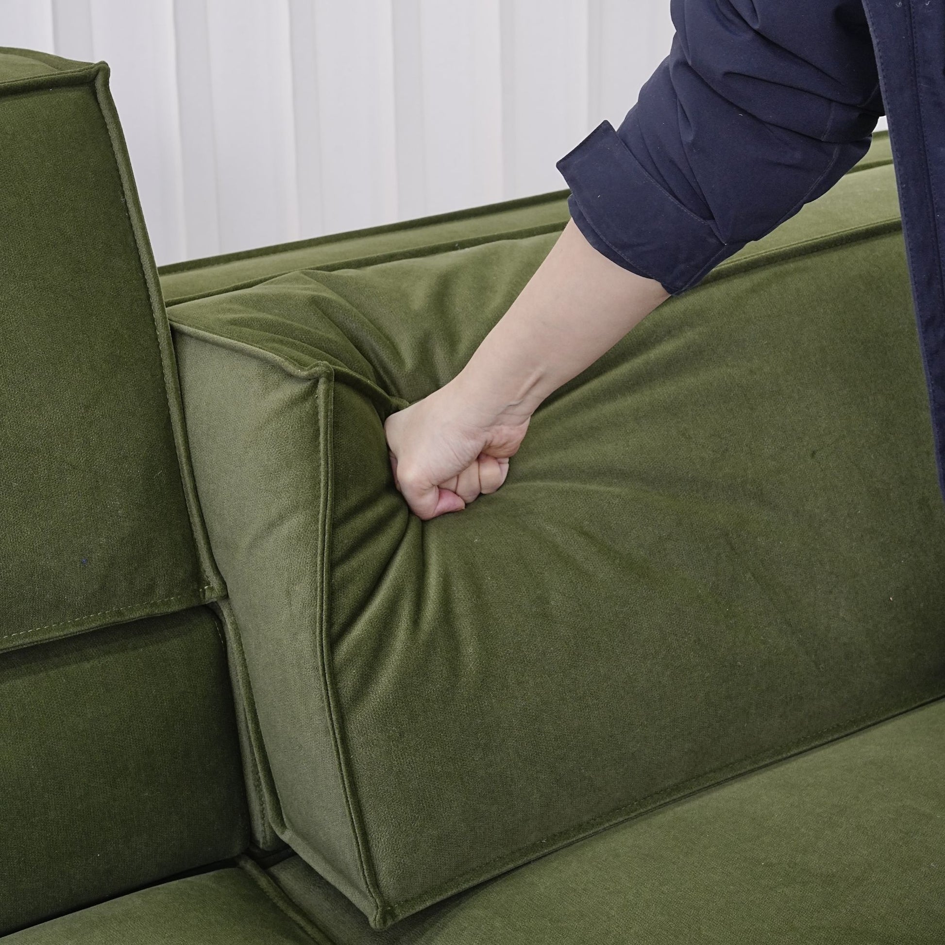 Hand pressing down on the adjustable backrest portion for Cubix fabric adjustable backrest sofa in green pet friendly fabric.