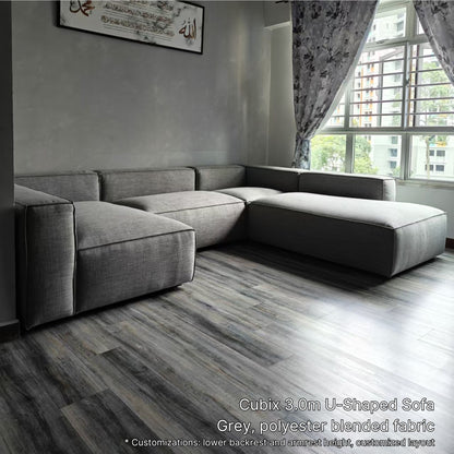 Gray Cubix 5 seater U-shaped sofa in a room with large windows and a gray paneled floor.