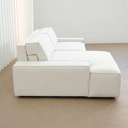 Beige sectional sofa in a minimalistic room with white walls and curtains.
