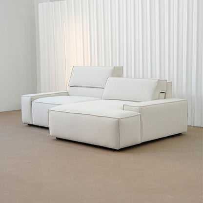 Beige sectional sofa in a minimalistic room with white curtains.
