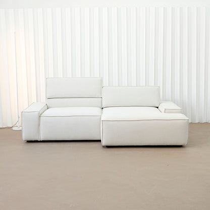 Beige sectional sofa in a minimalistic room with white walls and a brown floor.