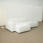White sectional sofa in a minimalistic room with a striped wall.