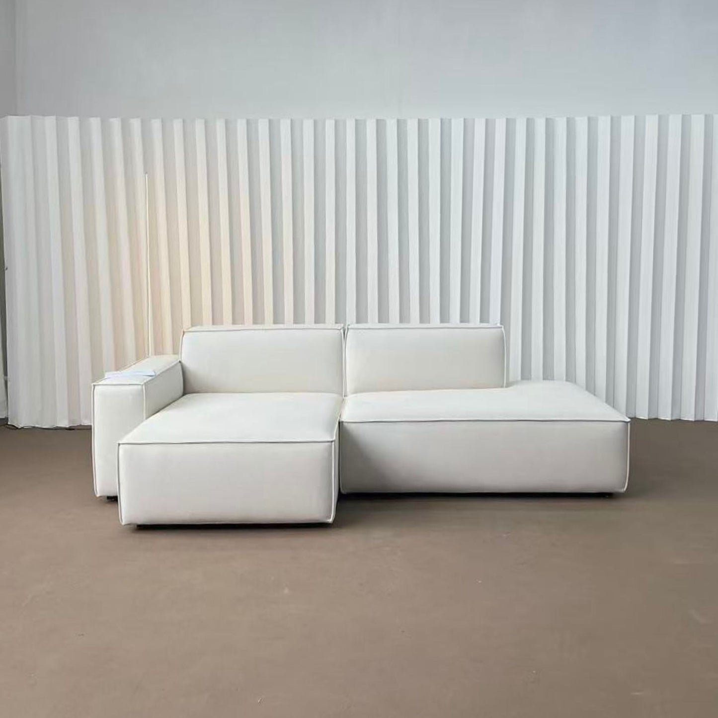 White sectional sofa against a white paneled wall.