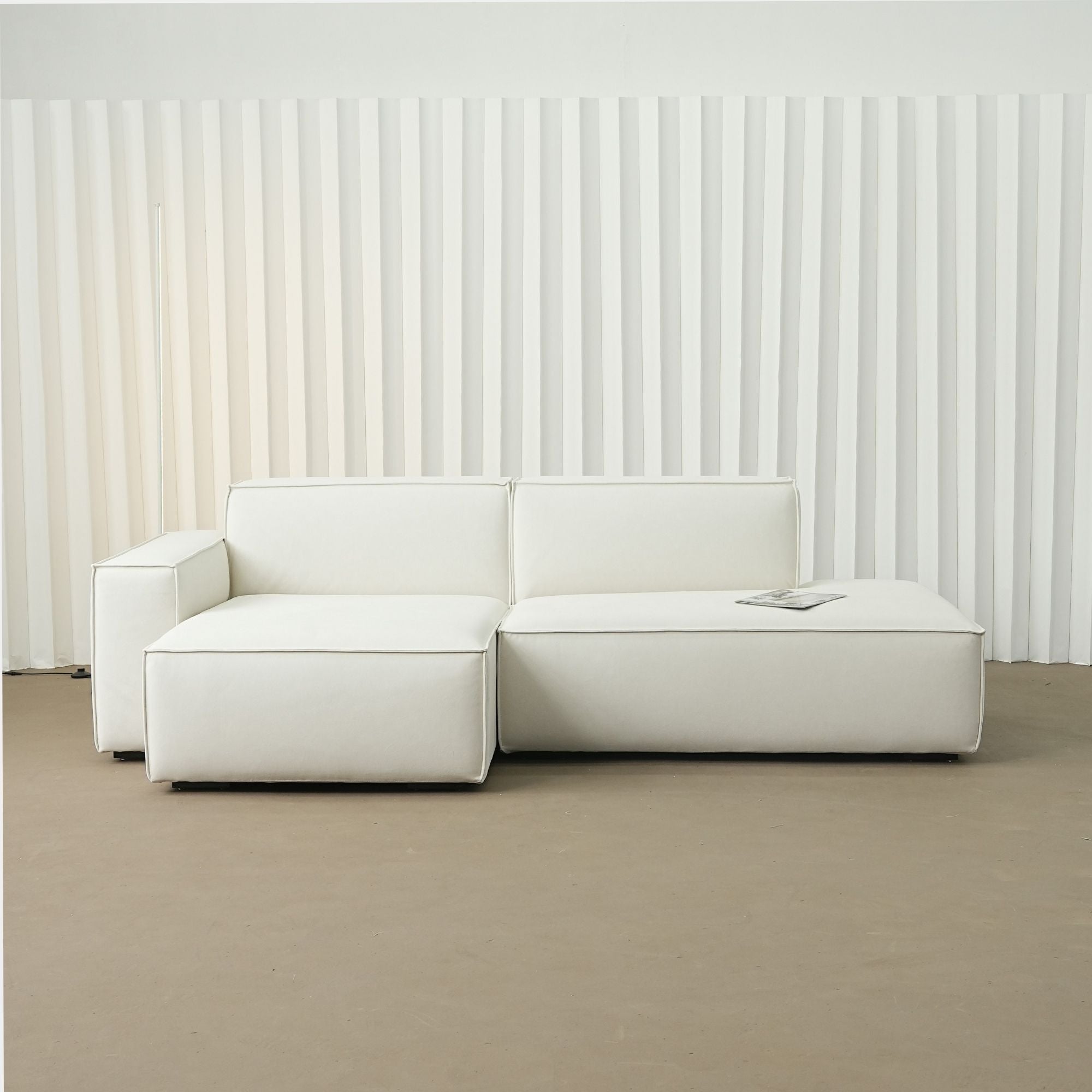 White sectional sofa against a white paneled wall.