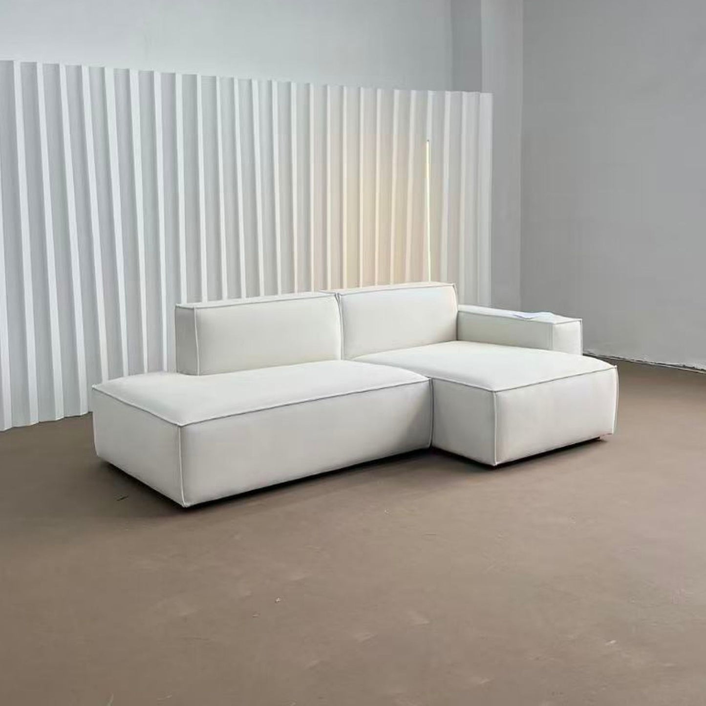White sectional sofa in a minimalistic room with a textured wall.