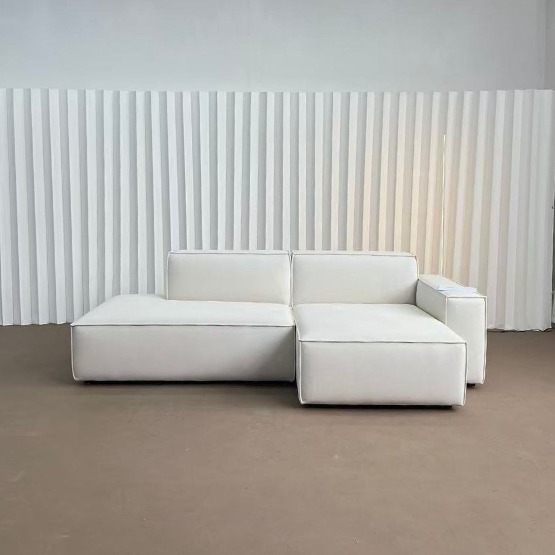 White sectional sofa against a white paneled wall.
