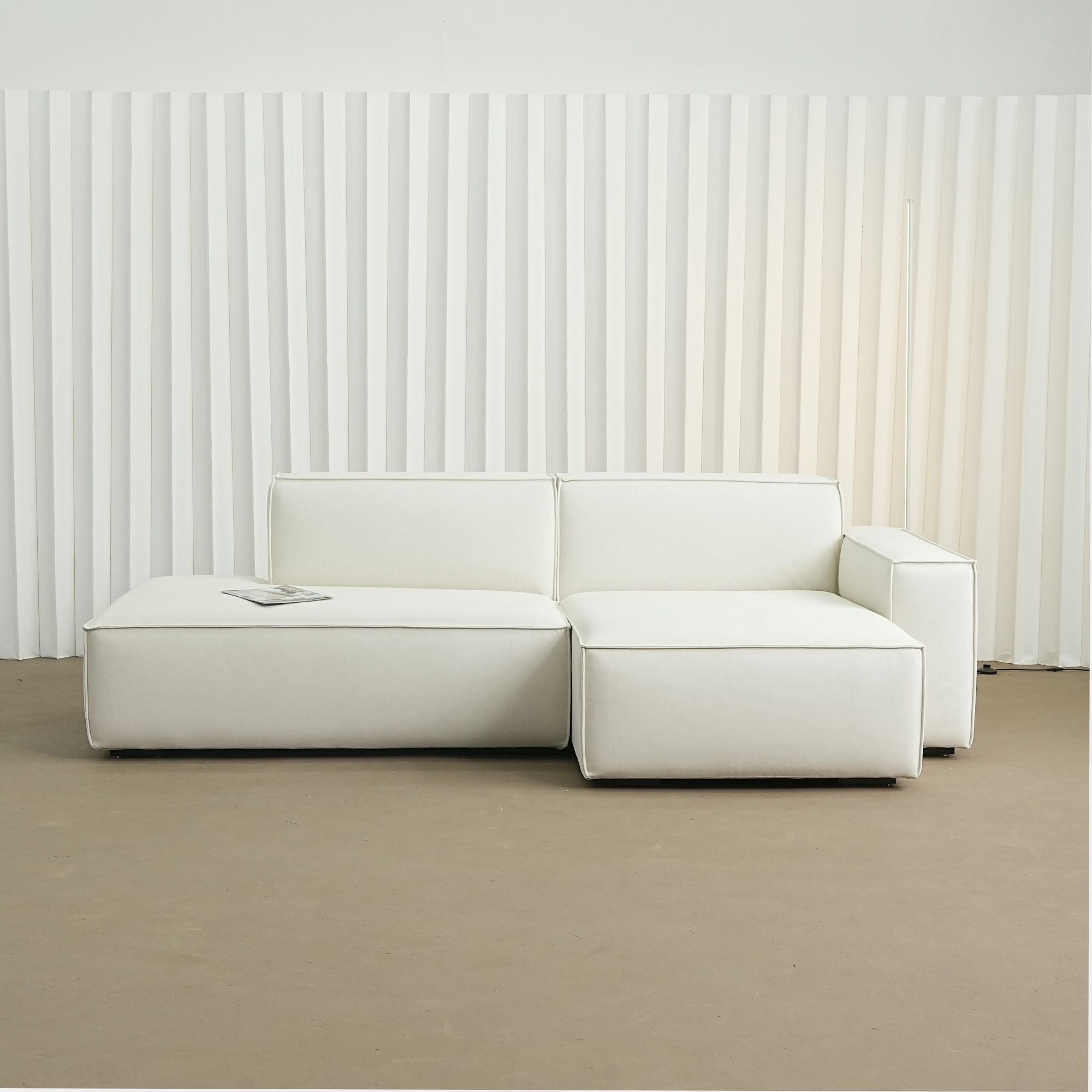 White sectional sofa against a white paneled wall.