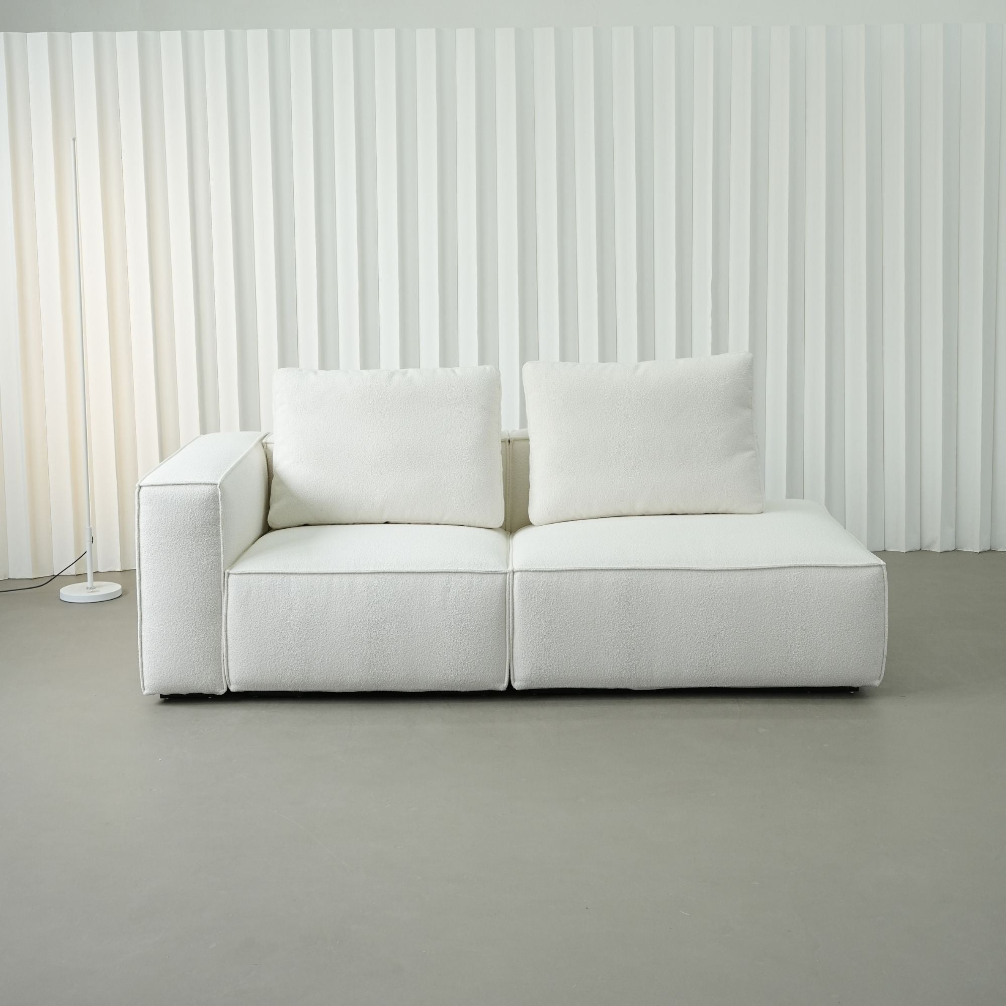 White sofa against a striped wall in a minimalistic room.