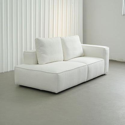 White sofa in a minimalistic room with light gray floor and white curtains.