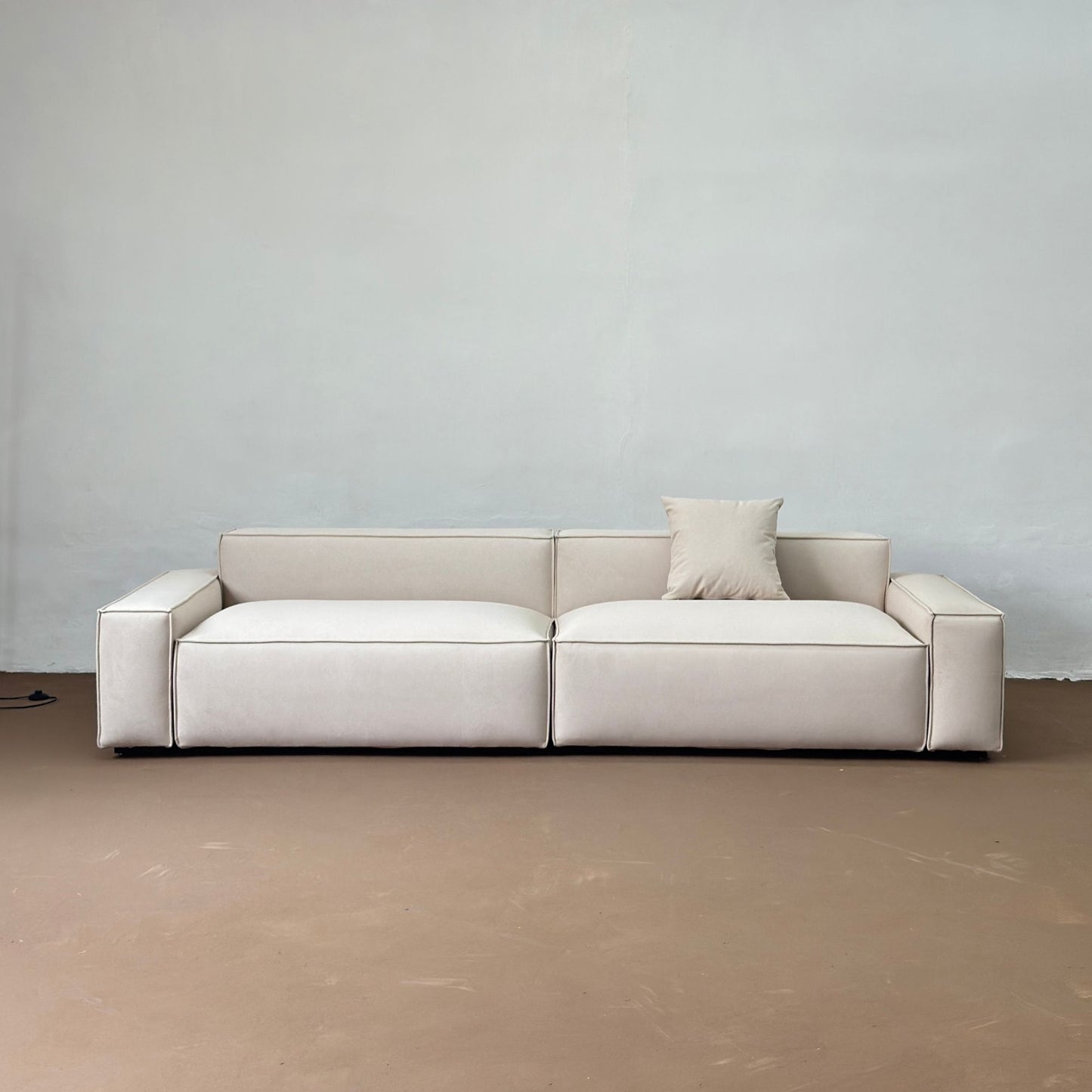 Beige sofa against a plain wall with a neutral floor.