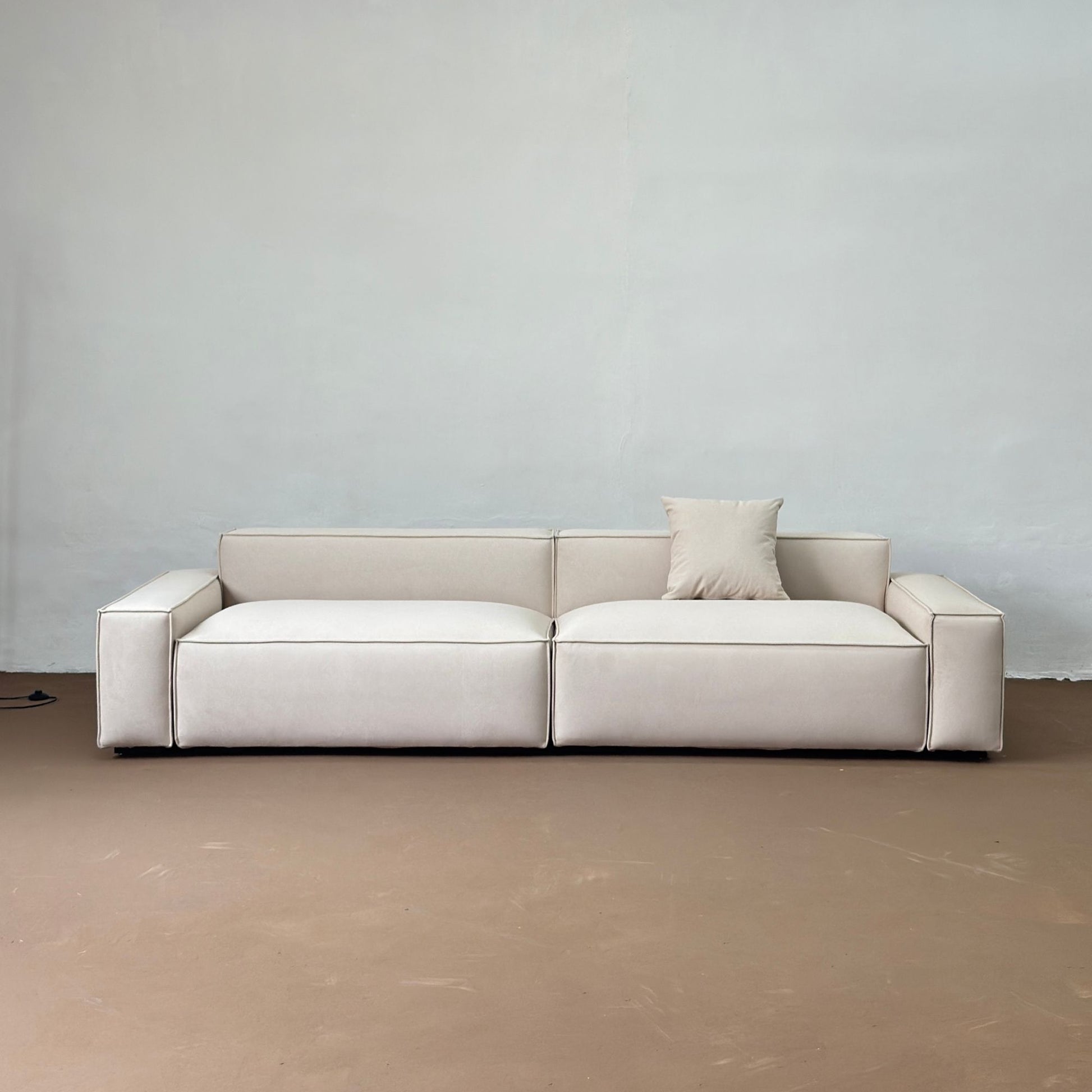 Beige sofa against a plain wall with a neutral floor.