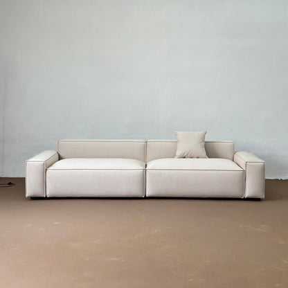 Beige sofa against a plain wall with a neutral floor.