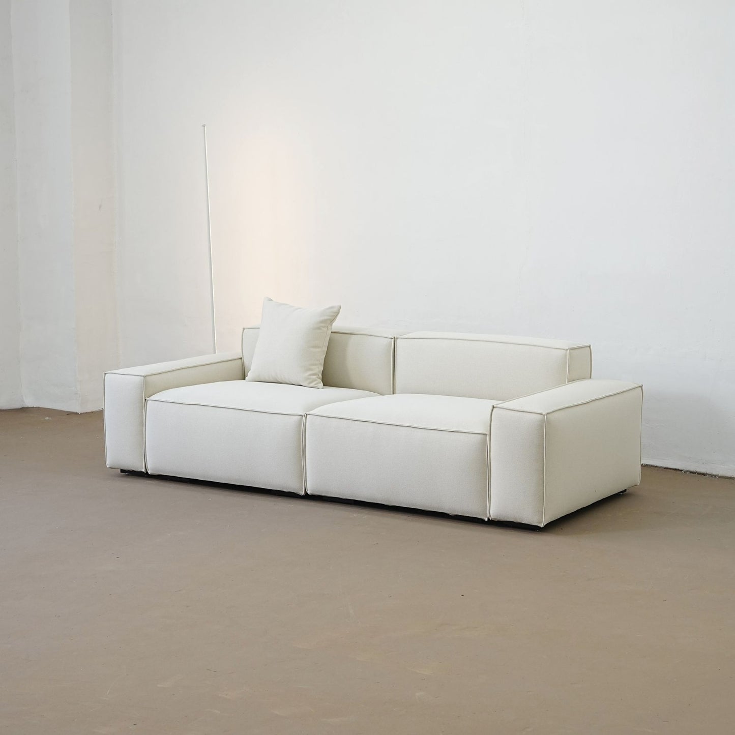White sofa in a minimalistic room with a plain white wall.