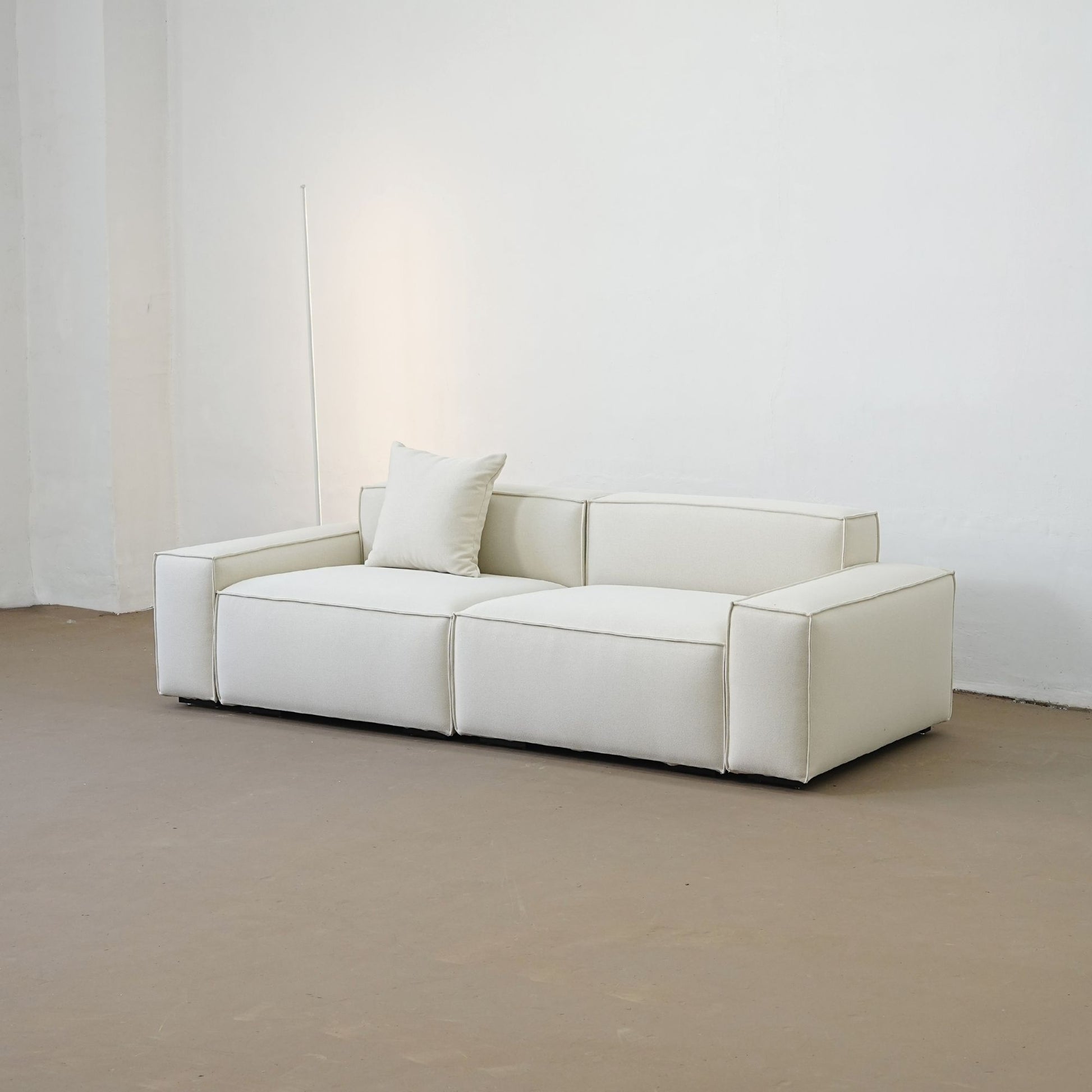 White sofa in a minimalistic room with a plain white wall.
