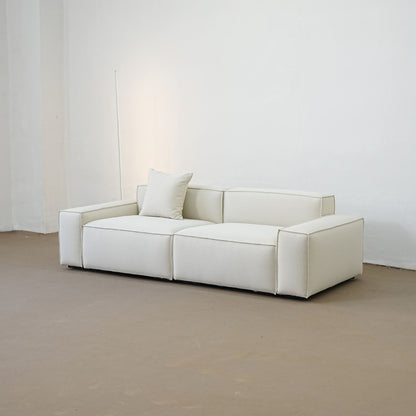 White sofa in a minimalistic room with a plain white wall.