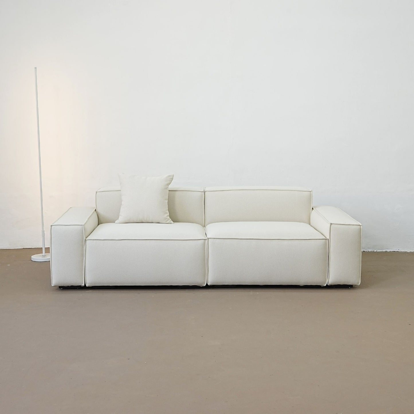 White sofa with a pillow against a plain white wall.