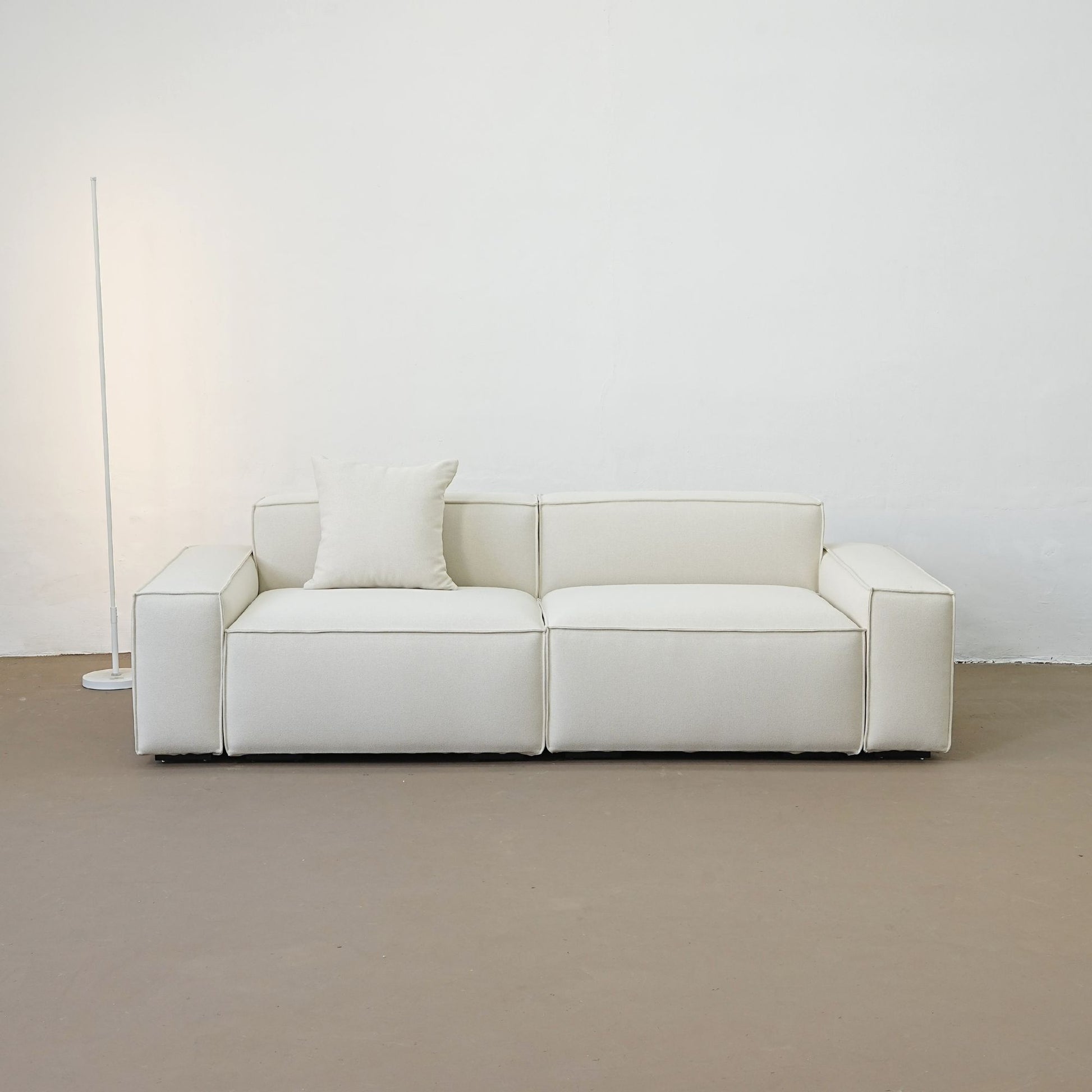 White sofa with a pillow against a plain white wall.