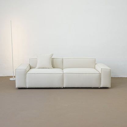 White sofa with a pillow against a plain white wall.