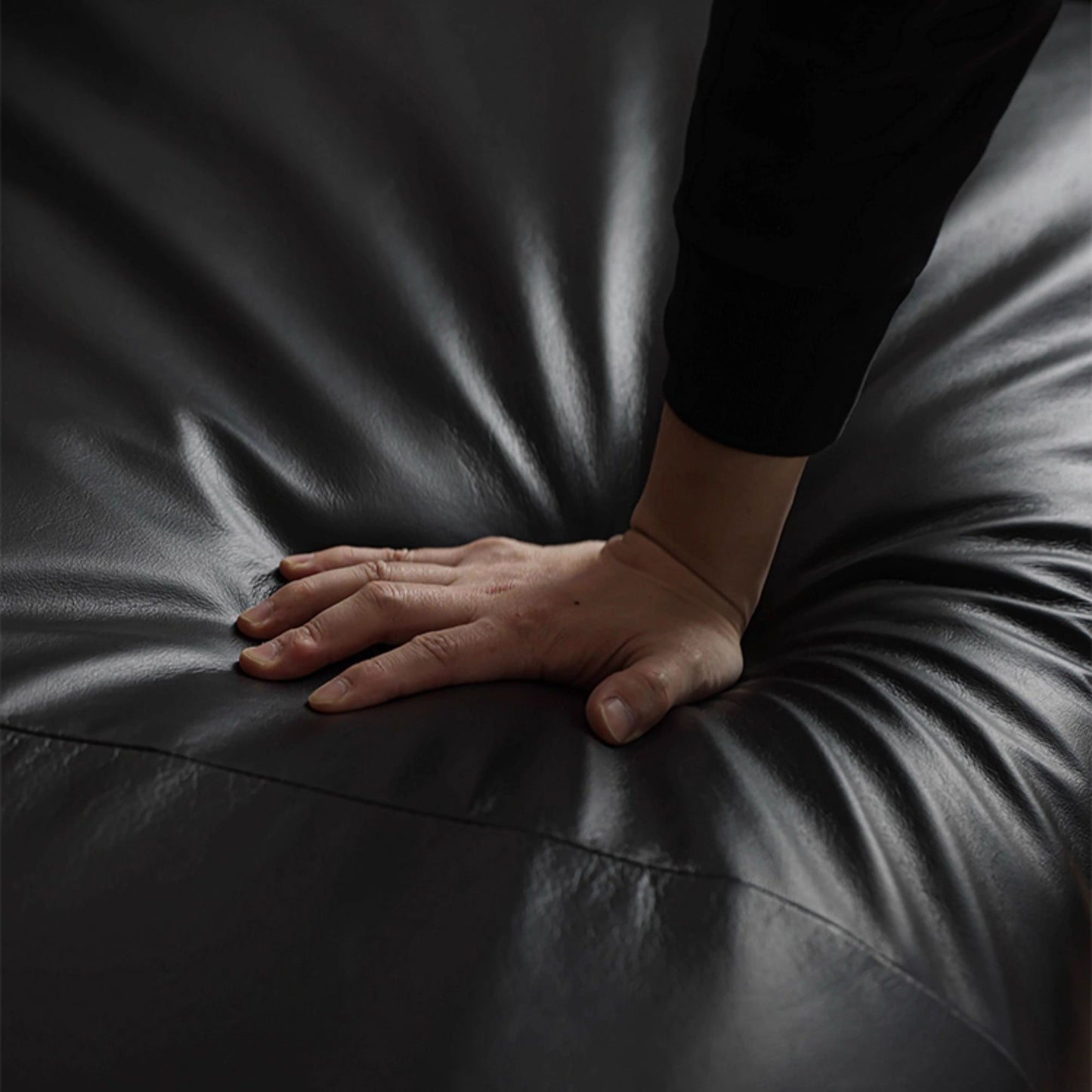 Hand pressing on Cuddle black leather sofa's seat cushion