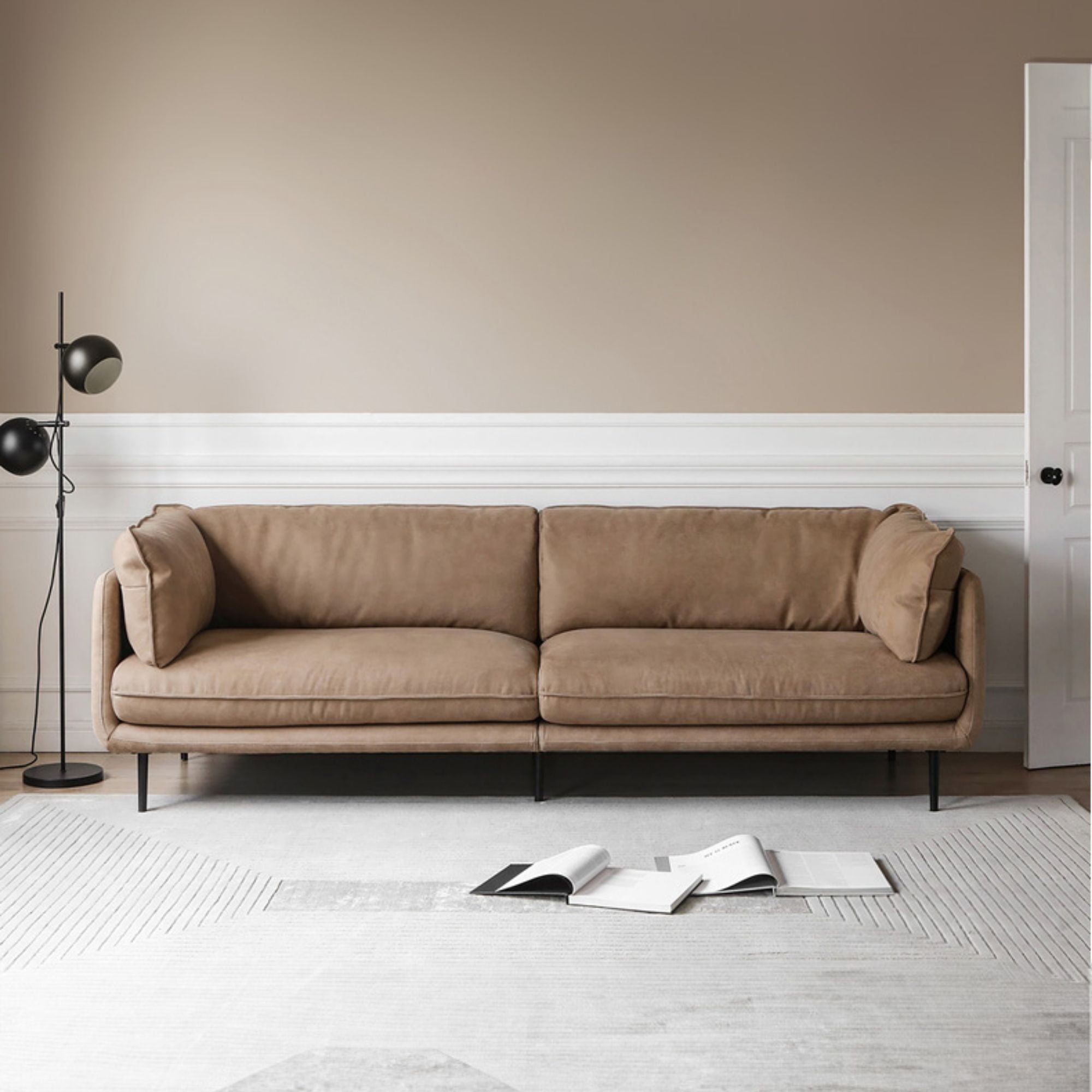 Brown sofa in a minimalistic living room with an open book on the floor.