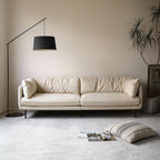White sofa in a living room with a black floor lamp and a plant.