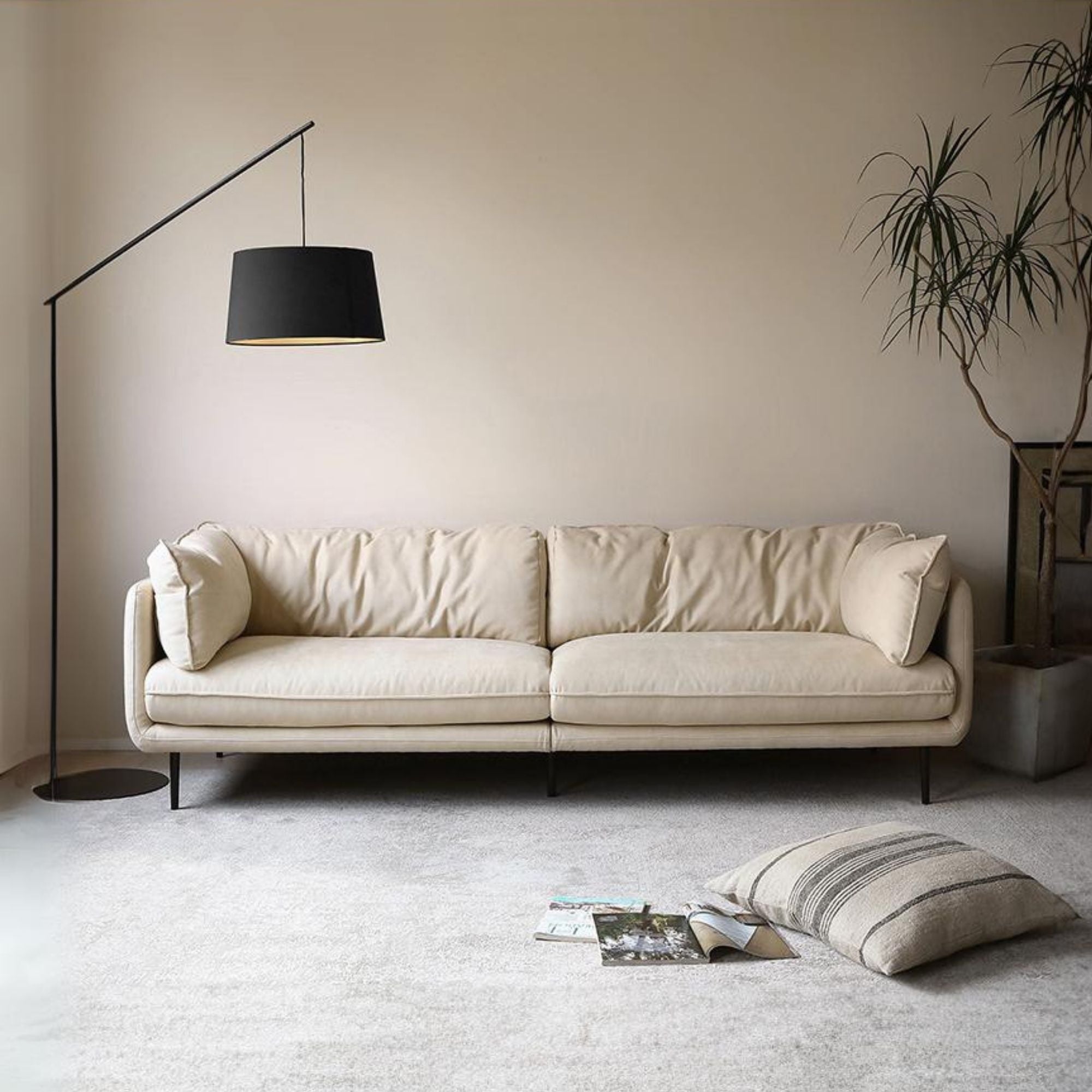White sofa in a living room with a black floor lamp and a plant.