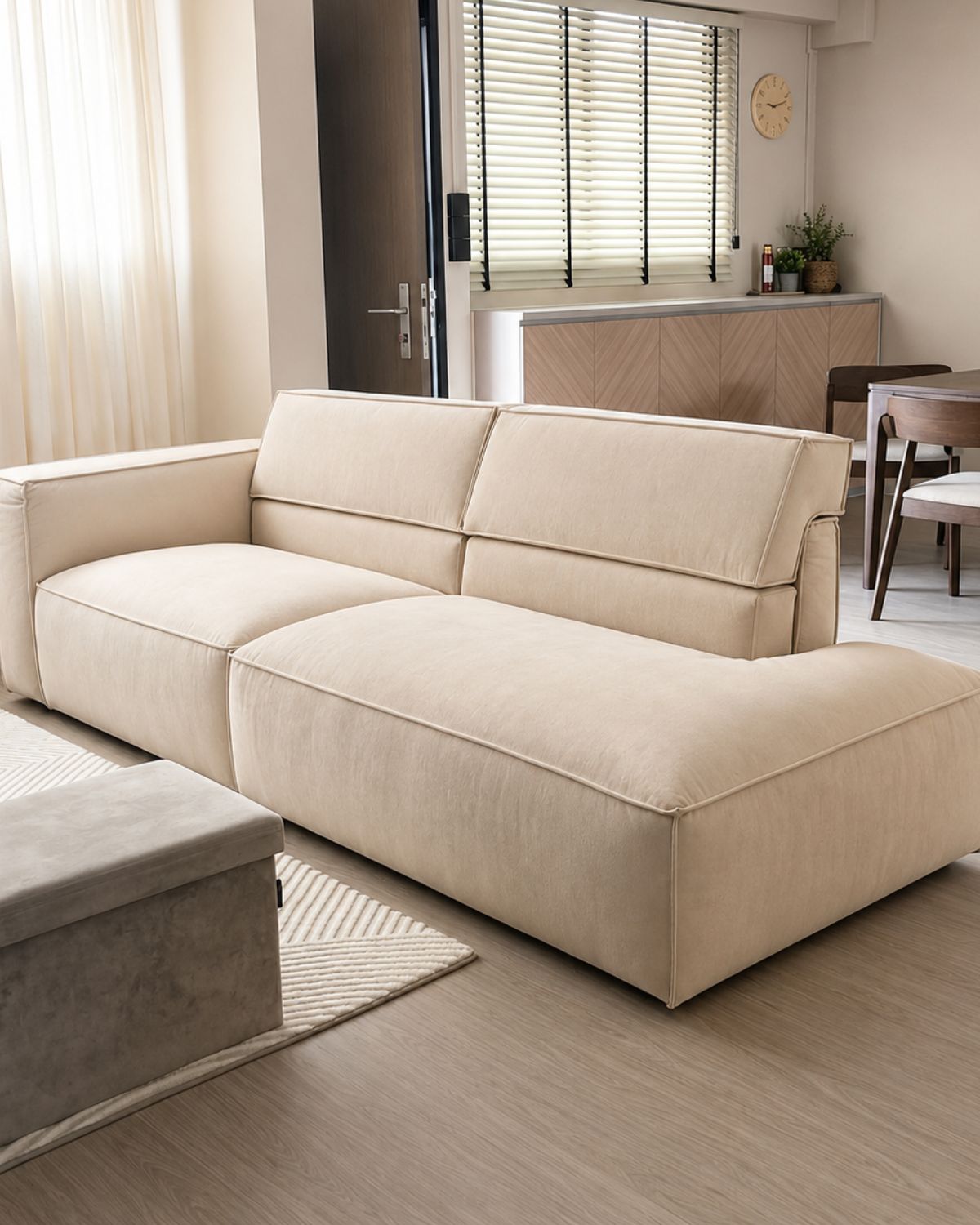 Beige pet friendly fabric sofa with adjustable backrest in a modern living room with large windows.