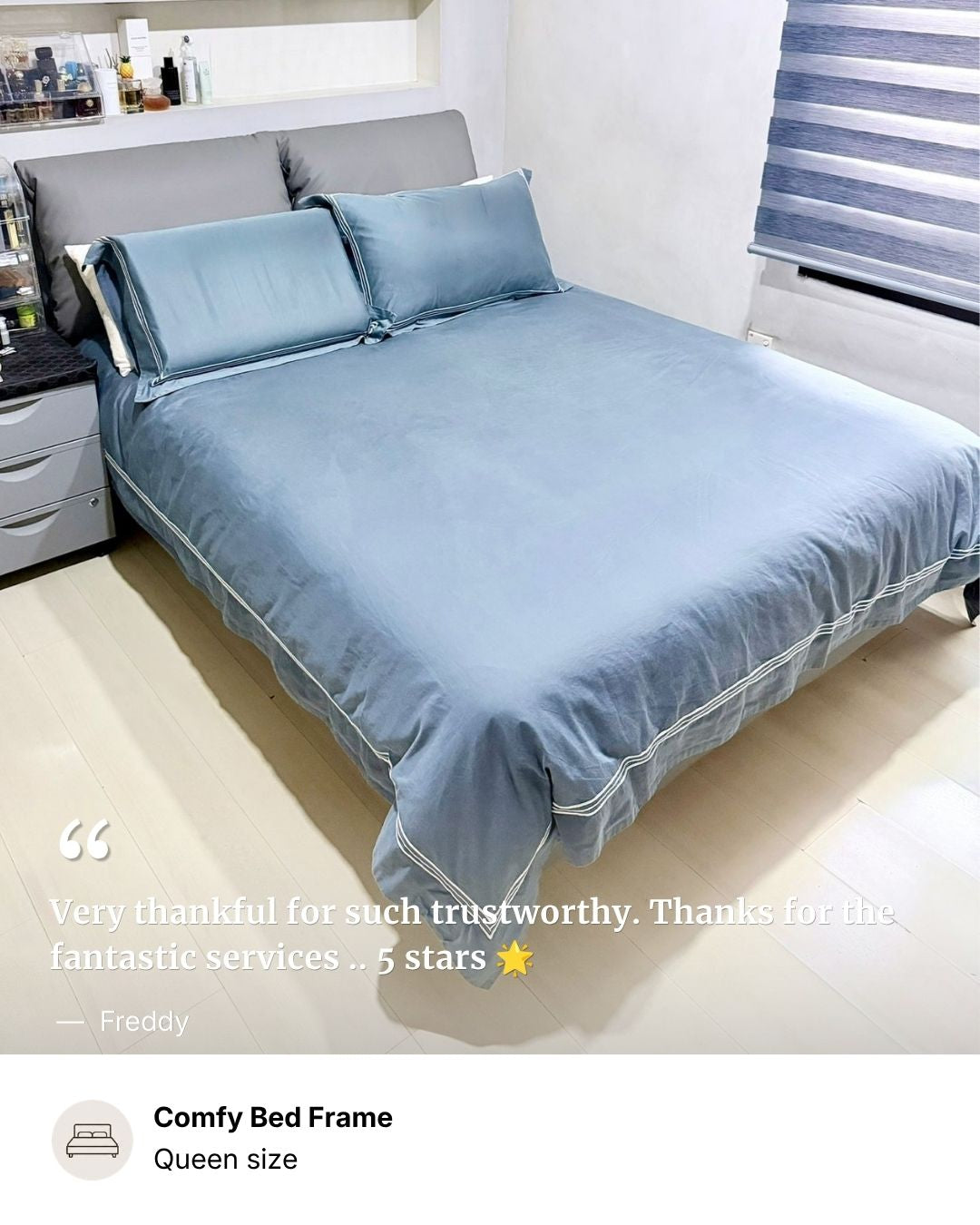 A bed dressed in a dusty blue bedding set with matching pillows and a duvet, shown in a bedroom setting. A text overlay at the bottom reads 'Comfy Bed Frame Queen size' and includes a customer testimonial.