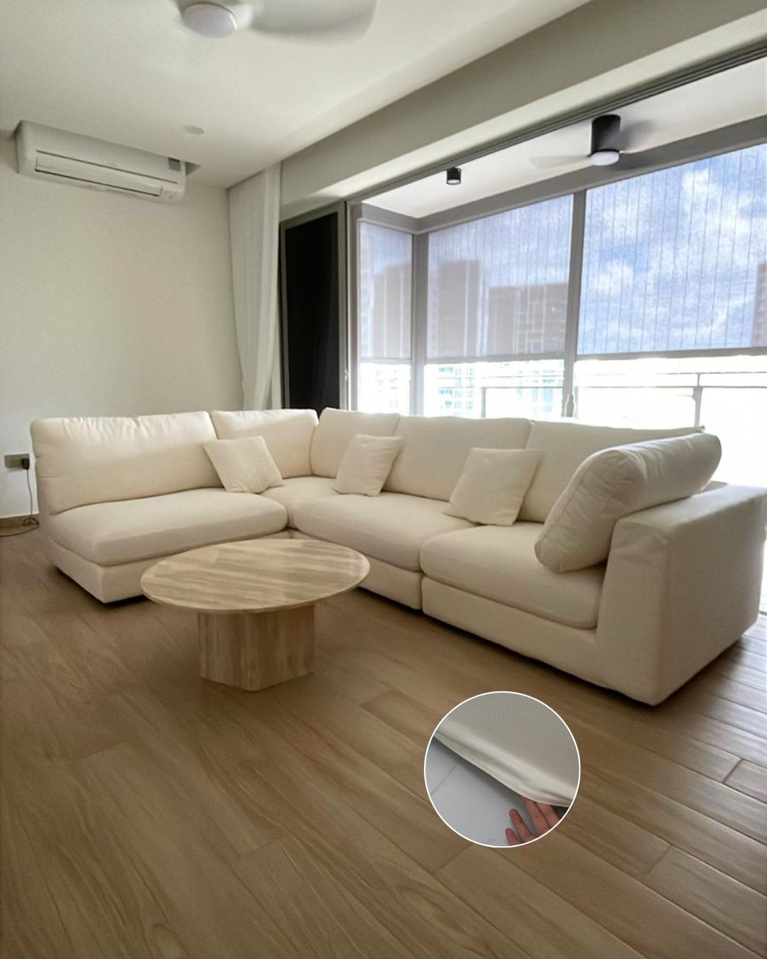 A cream-colored modular sectional sofa in a modern living room setting, featuring a round wooden coffee table and a circular inset demonstrating the removable fabric cover.