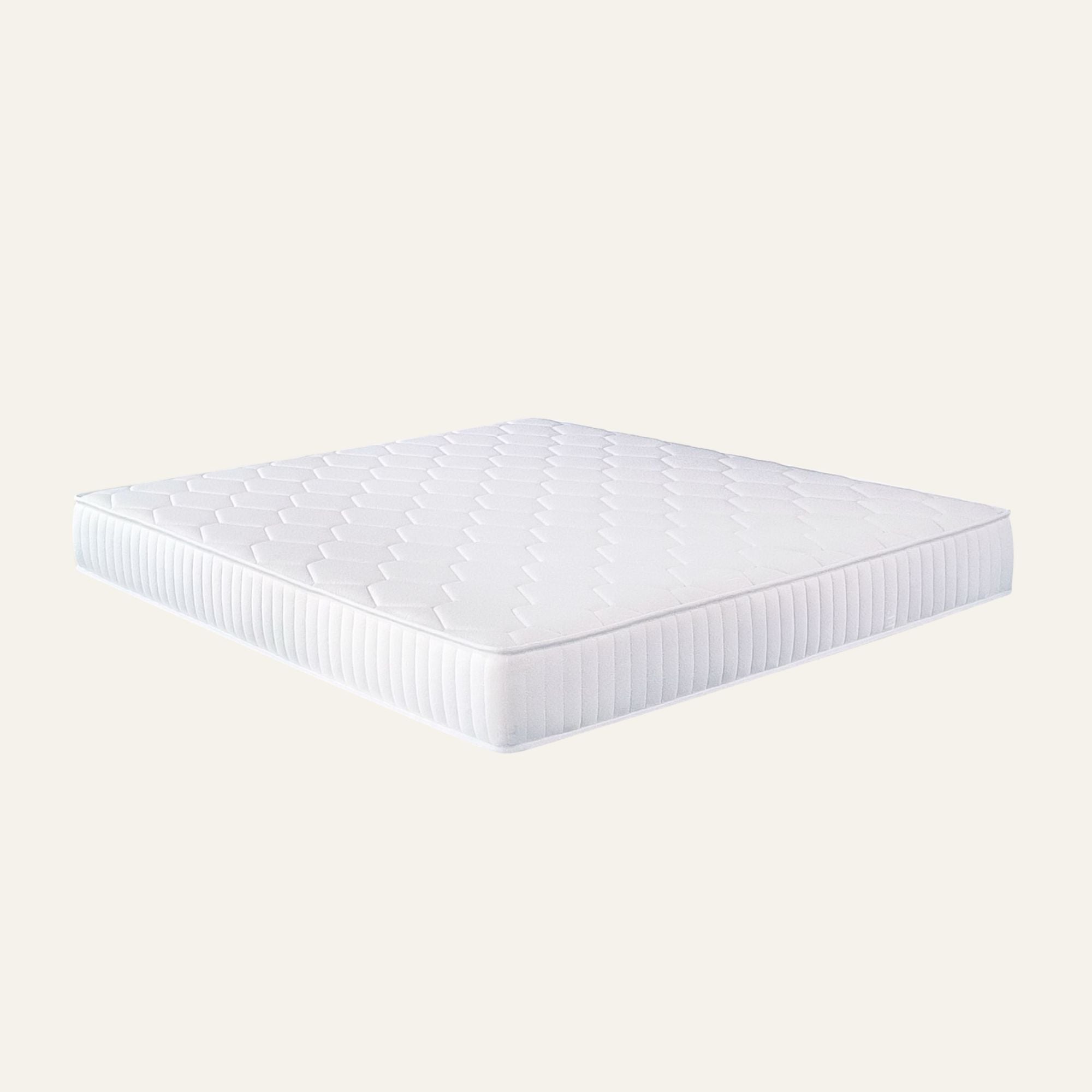 A white quilted mattress topper or mattress shown floating at an angle against a solid light beige background.