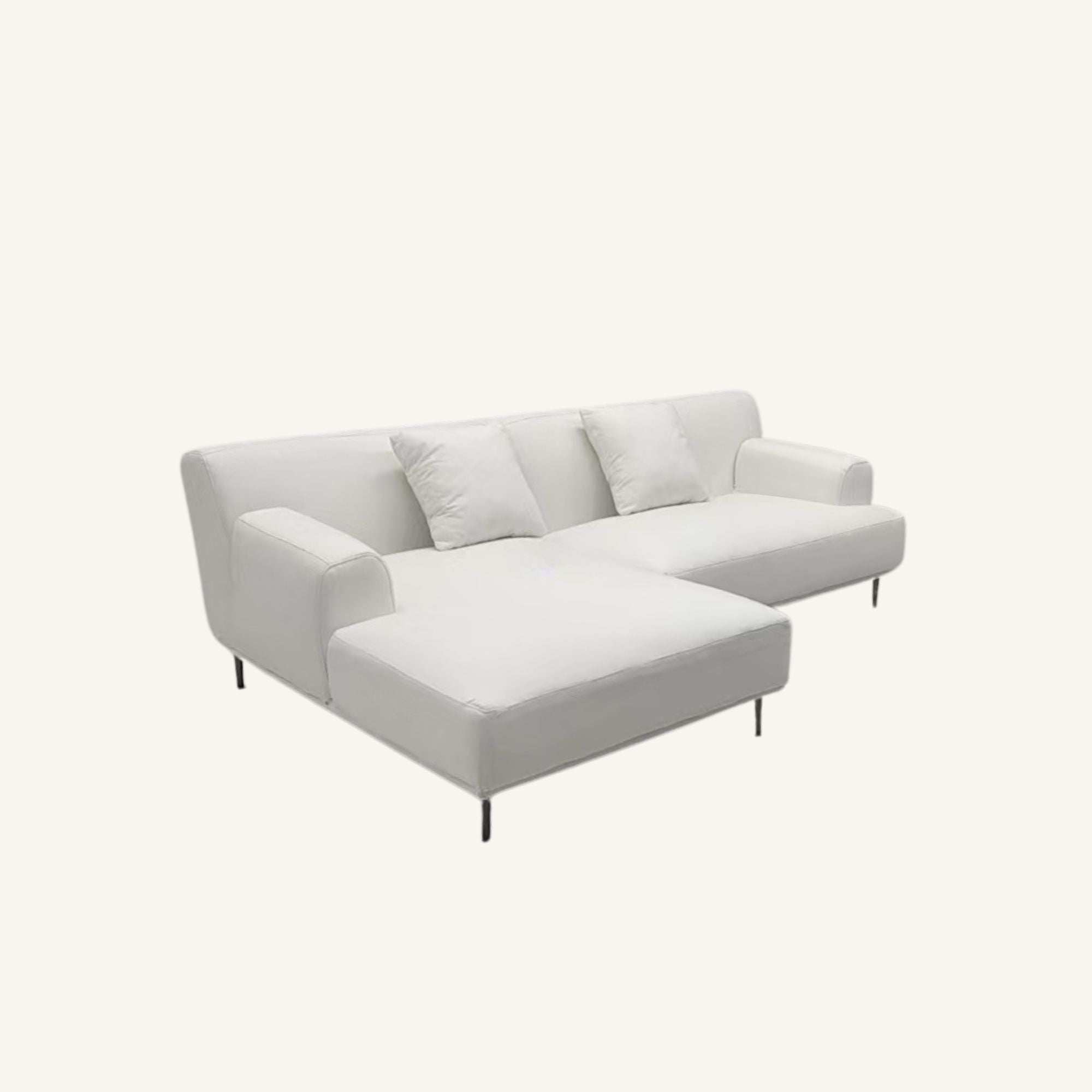 A modern white sectional sofa with a chaise lounge and two matching throw pillows, shown on a plain off-white background.