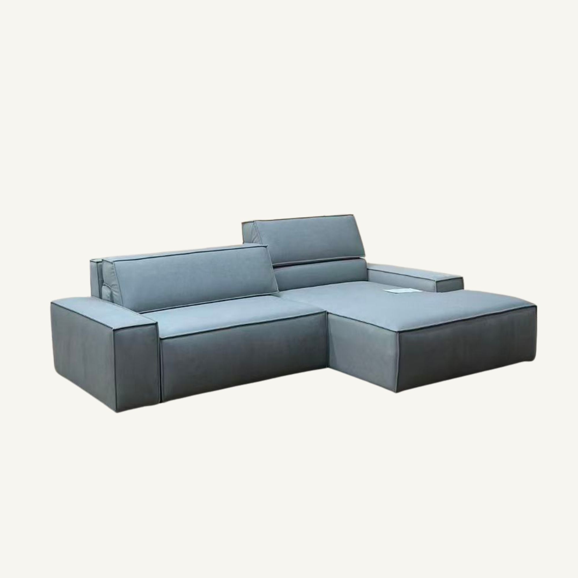 A modern modular sectional sofa in a muted gray fabric, featuring a chaise lounge on the right and a left armrest section, shown against a plain off-white background.