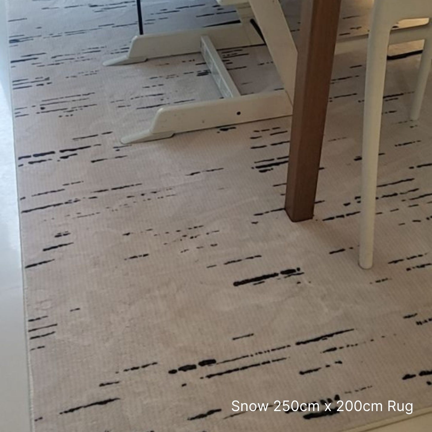 Beige rug with black abstract pattern under a table and chairs