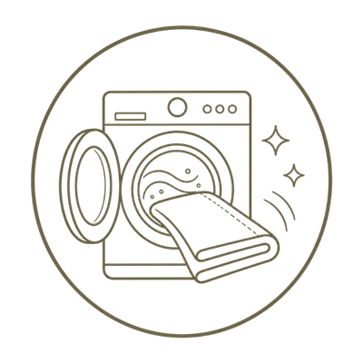 A minimalist line-art icon depicting a front-loading washing machine with a folded sofa covers being washed, enclosed in a circular border on a white background.