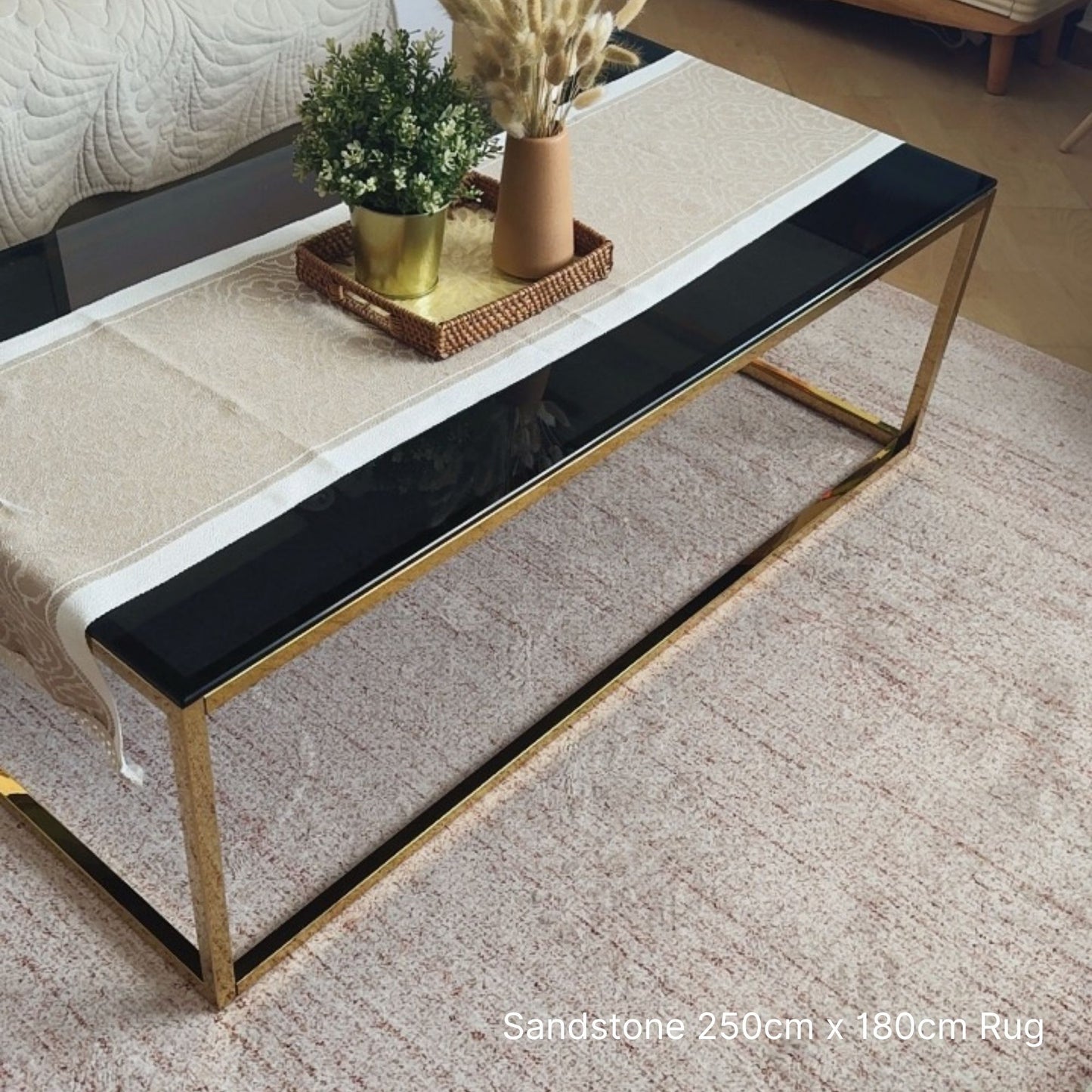 Coffee table with a black top and gold frame on a sandstone rug