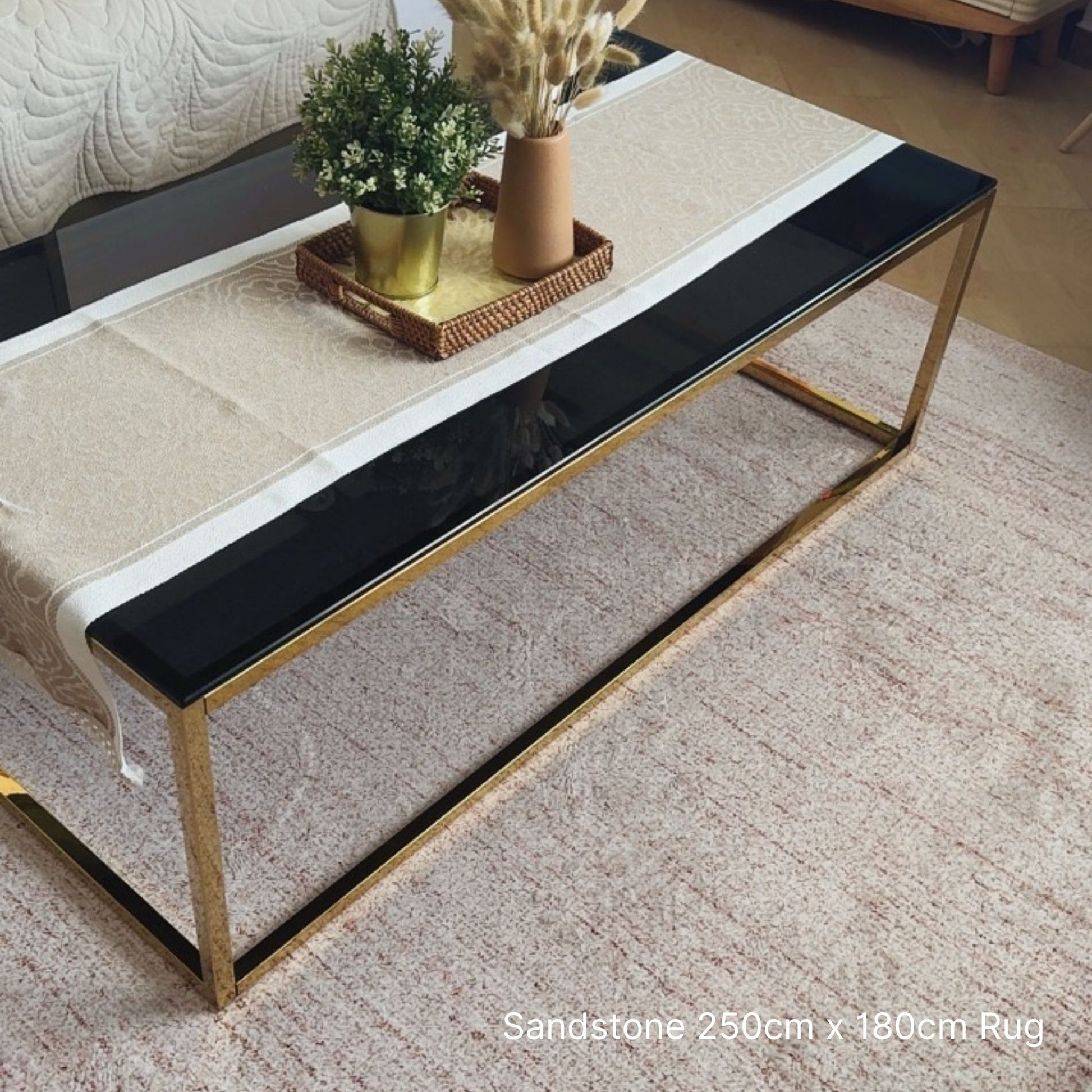 Coffee table with a black top and gold frame on a sandstone rug