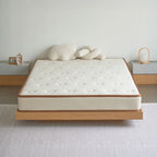 Mattress on a wooden bed frame with decorative pillows in a minimalistic room.
