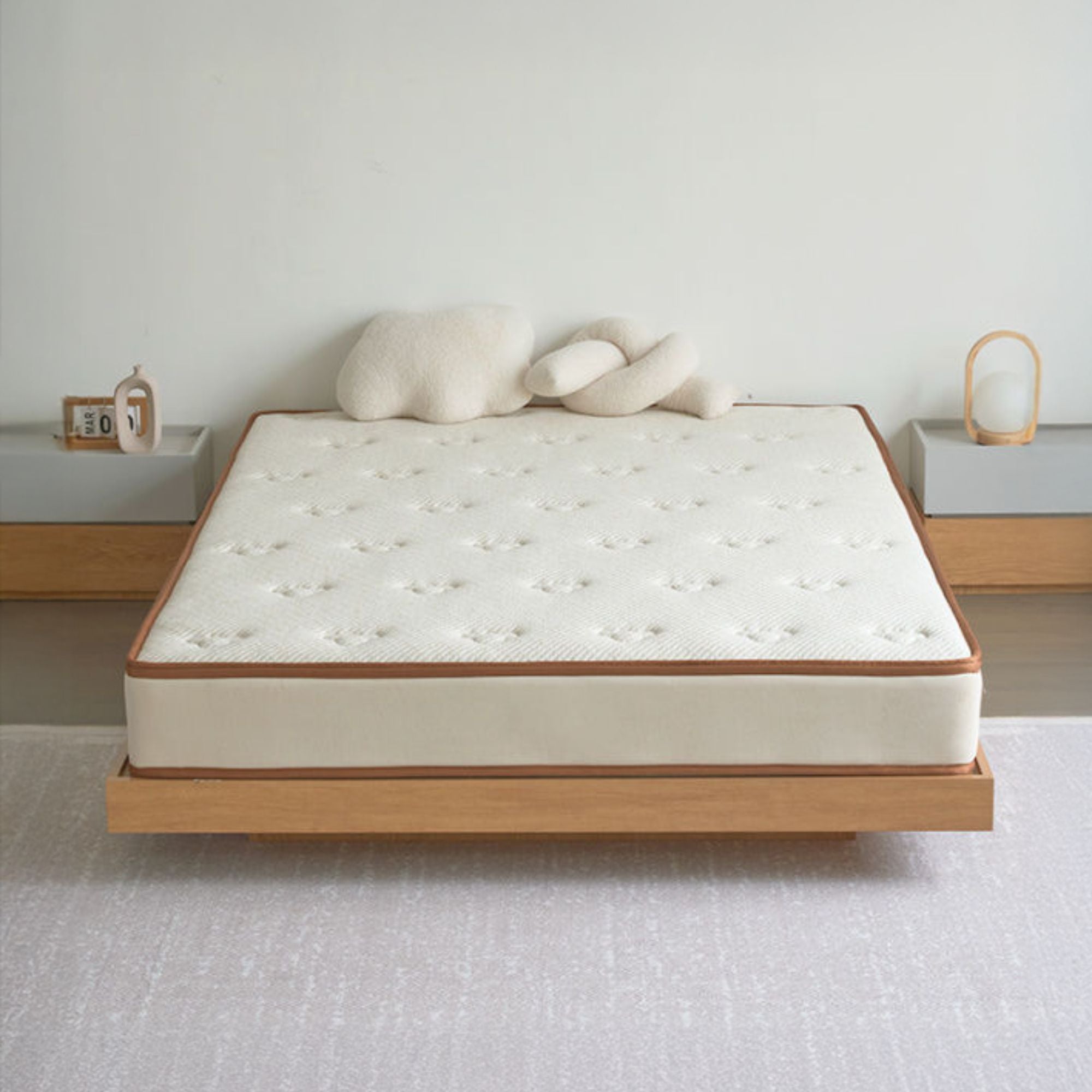 Mattress on a wooden bed frame with decorative pillows in a minimalistic room.