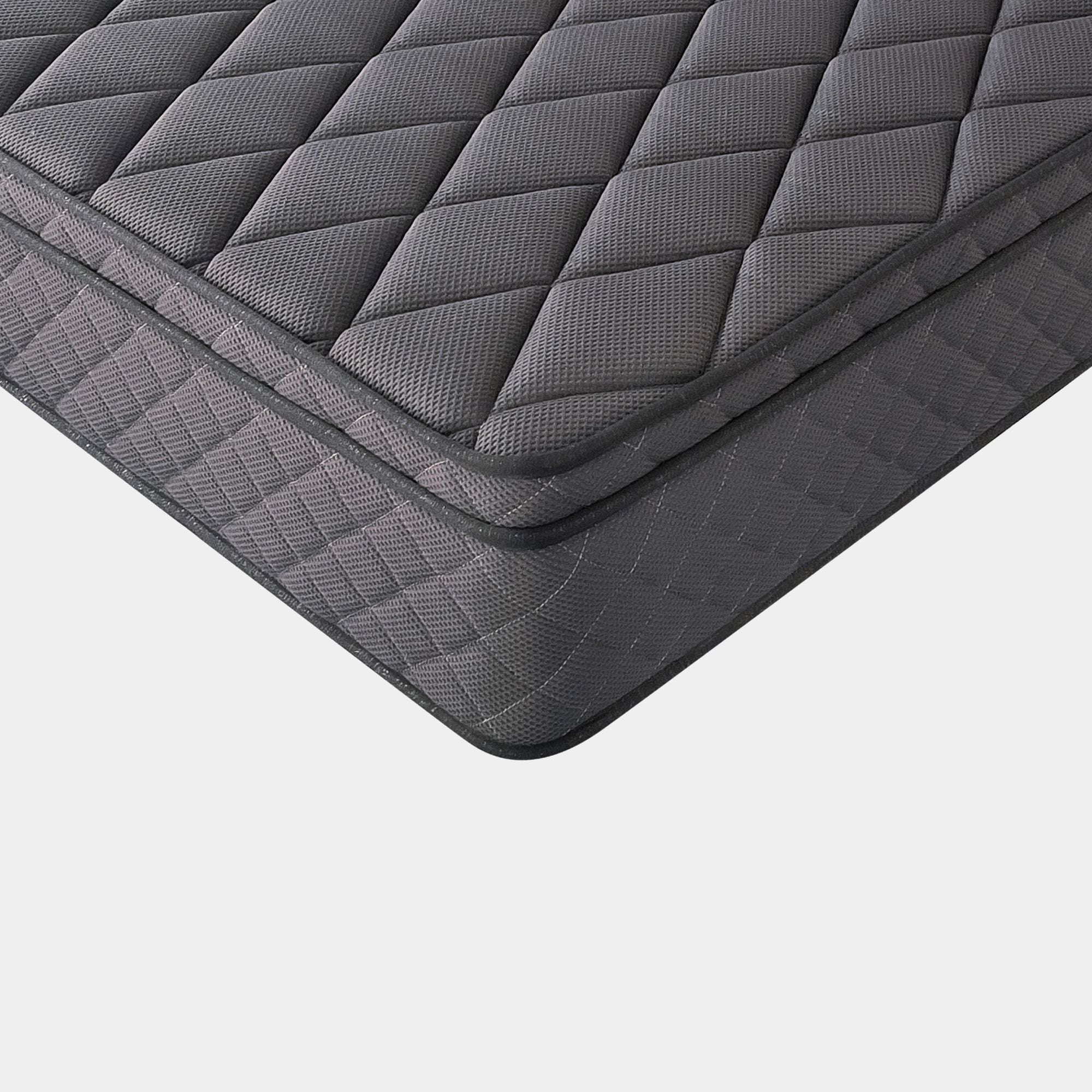 A close-up studio shot of a dark gray quilted mattress corner, showing the diamond-patterned top and textured side edge against a light gray background.