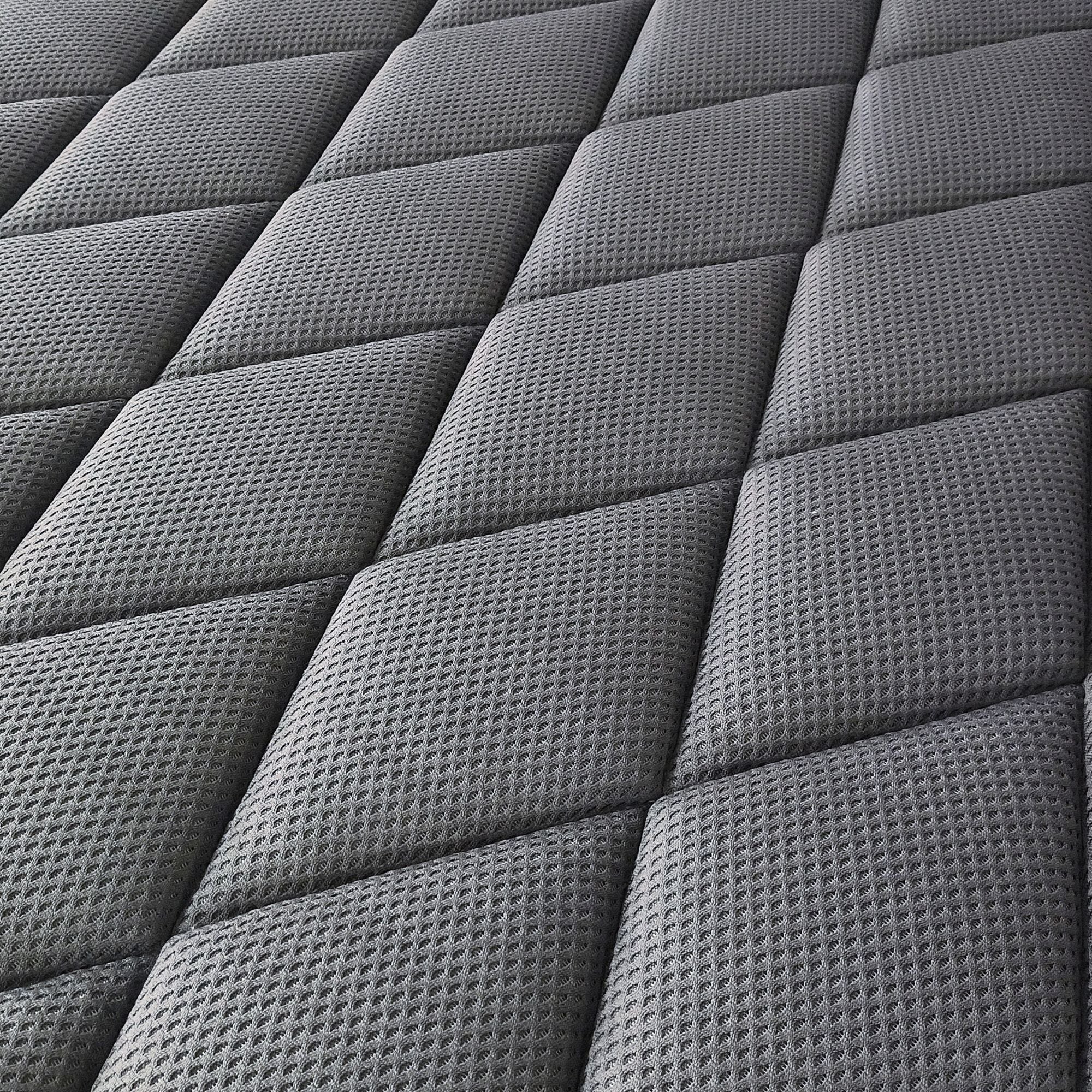 Close-up of a dark gray quilted mattress or cushion surface with a textured diamond pattern.