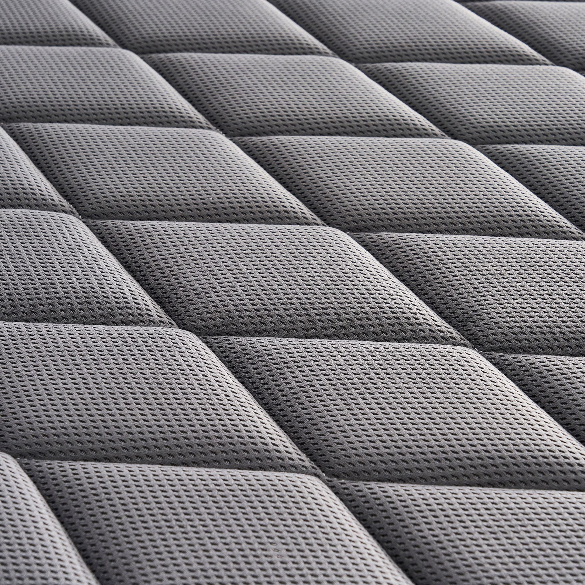 Close-up of a dark gray quilted mattress topper with a textured diamond pattern.