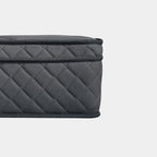 Close-up of a dark gray quilted fabric mattress with a textured woven pattern and black trim, shown against a light gray background.