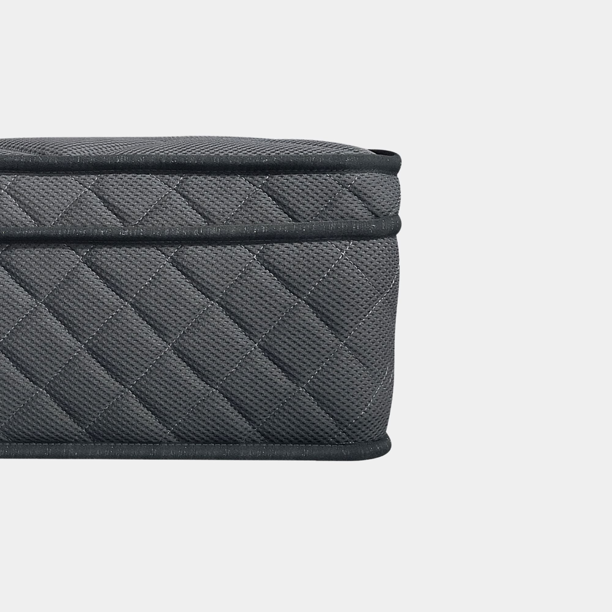Close-up of a dark gray quilted fabric mattress with a textured woven pattern and black trim, shown against a light gray background.