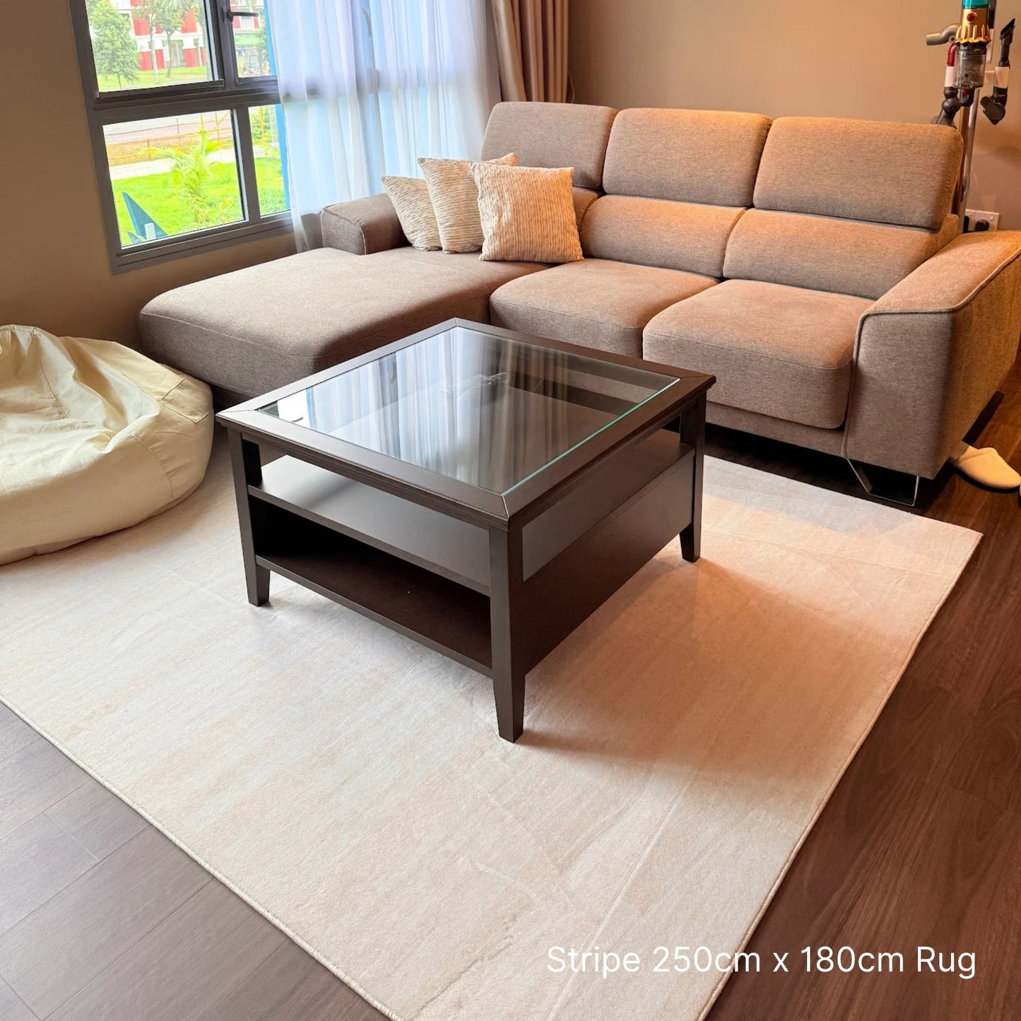 Living room with a beige sectional sofa, coffee table, and striped rug.