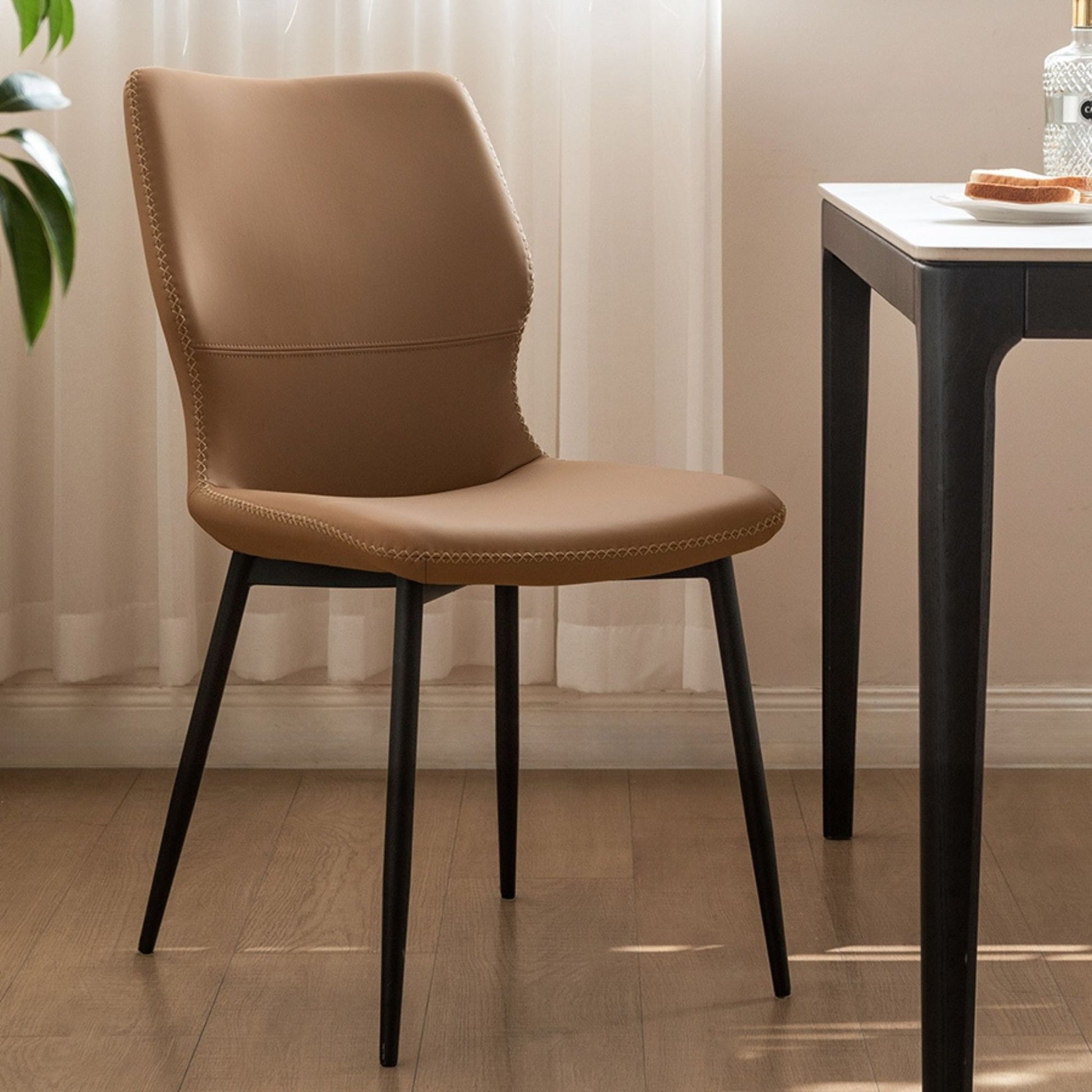 Brown chair with black legs in a room with a table and plant