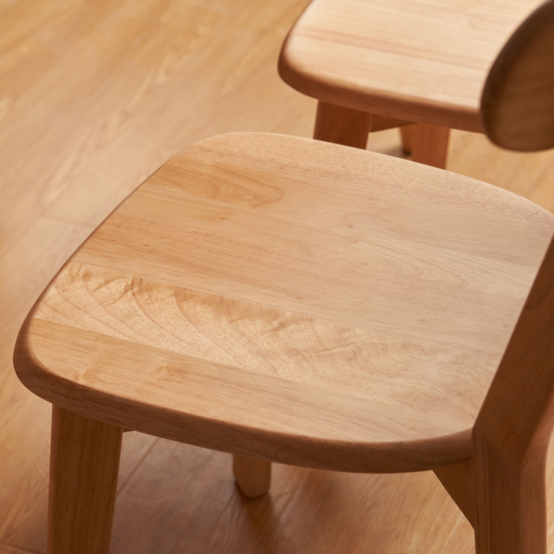 Close-up of a wooden chair seat on a wooden floor