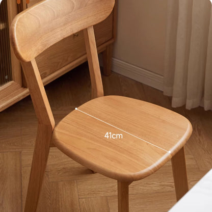 Wooden chair with a measurement label on the seat in a room setting.