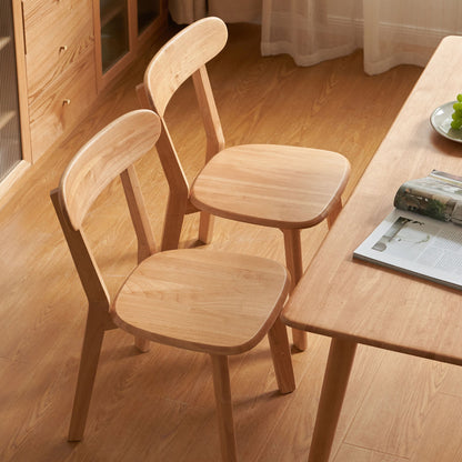 Two wooden chairs and a table with a magazine on a wooden table.