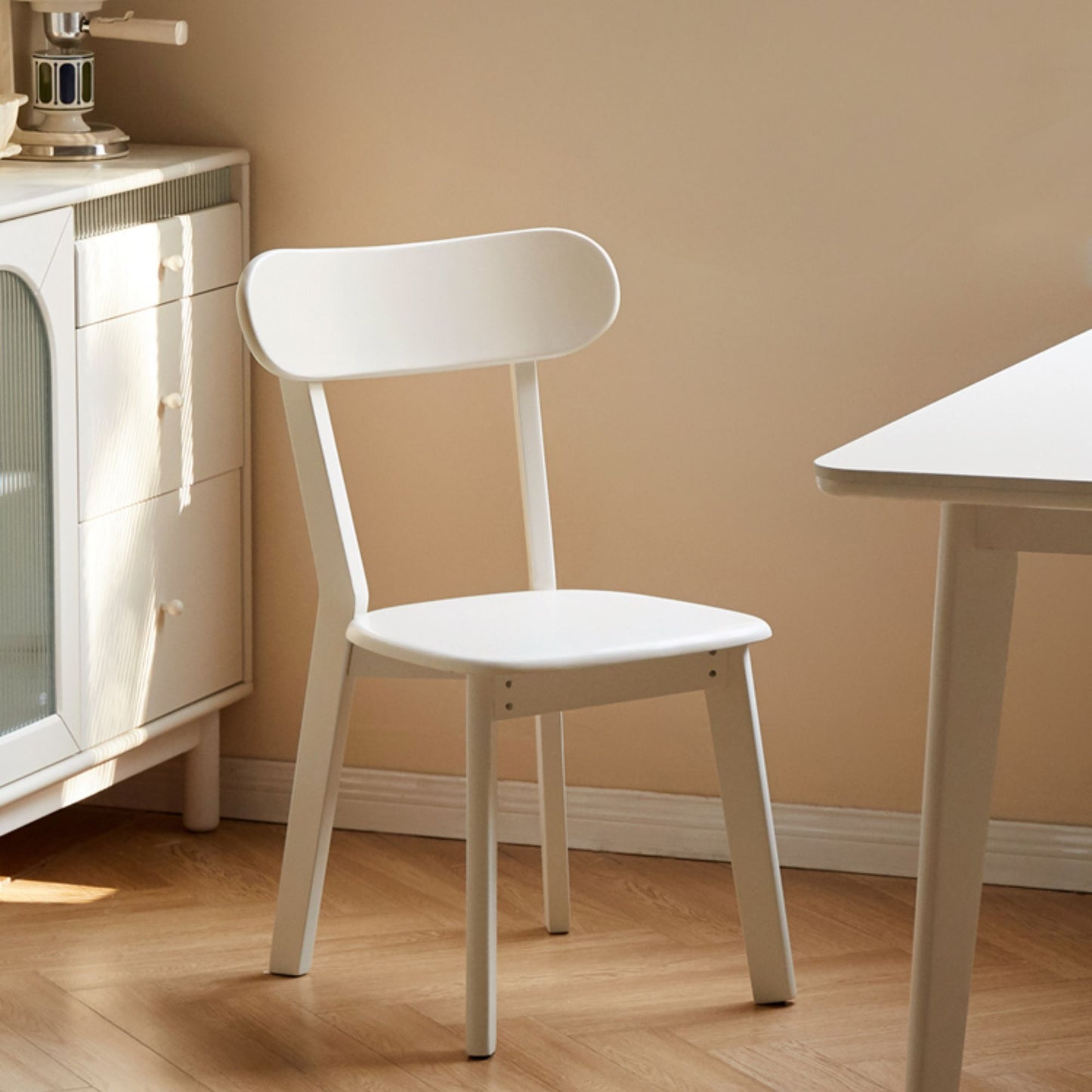 White chair in a room with a beige wall and wooden floor.
